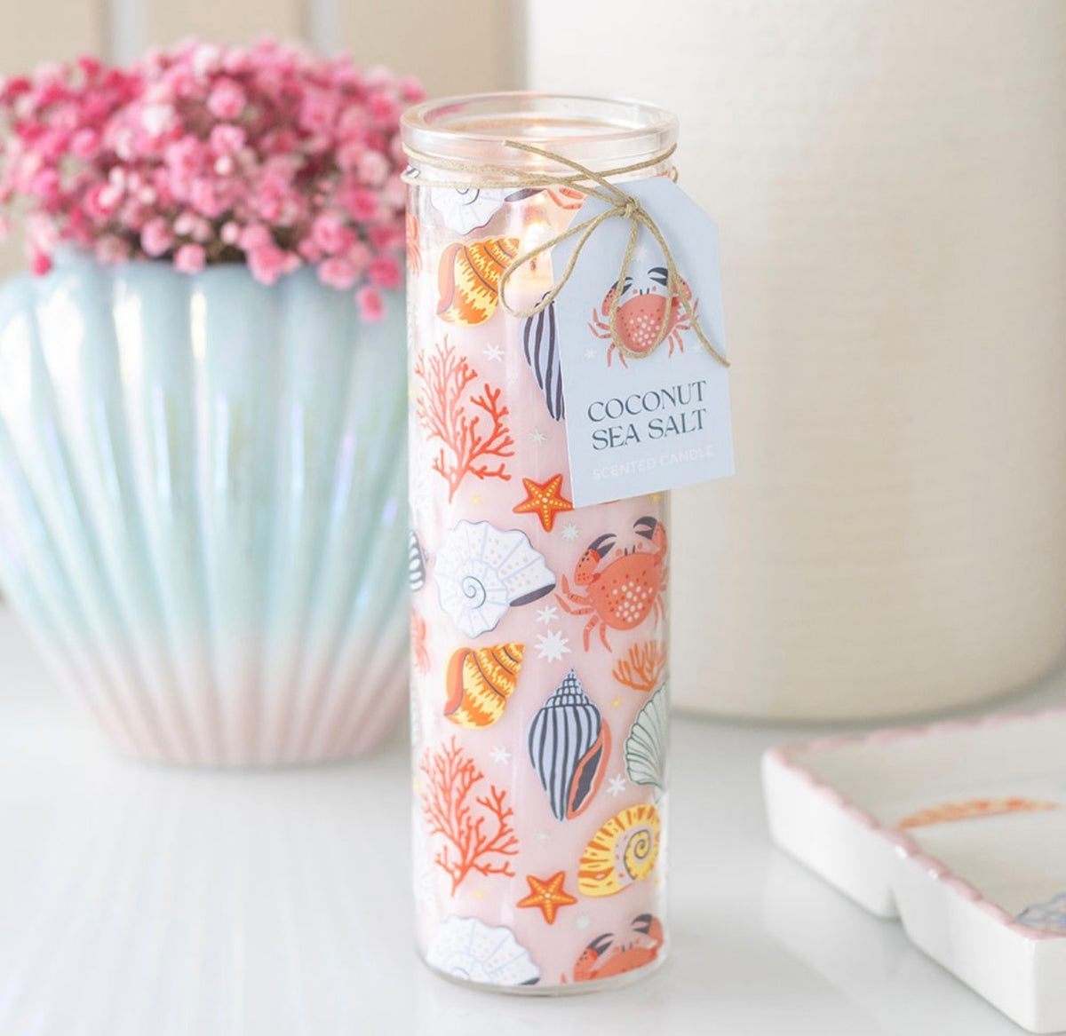 VELA DE TUBO CON ESTAMPADO DE CONCHAS EN TONOS PASTEL, AROMA A COCO Y SAL MARINA